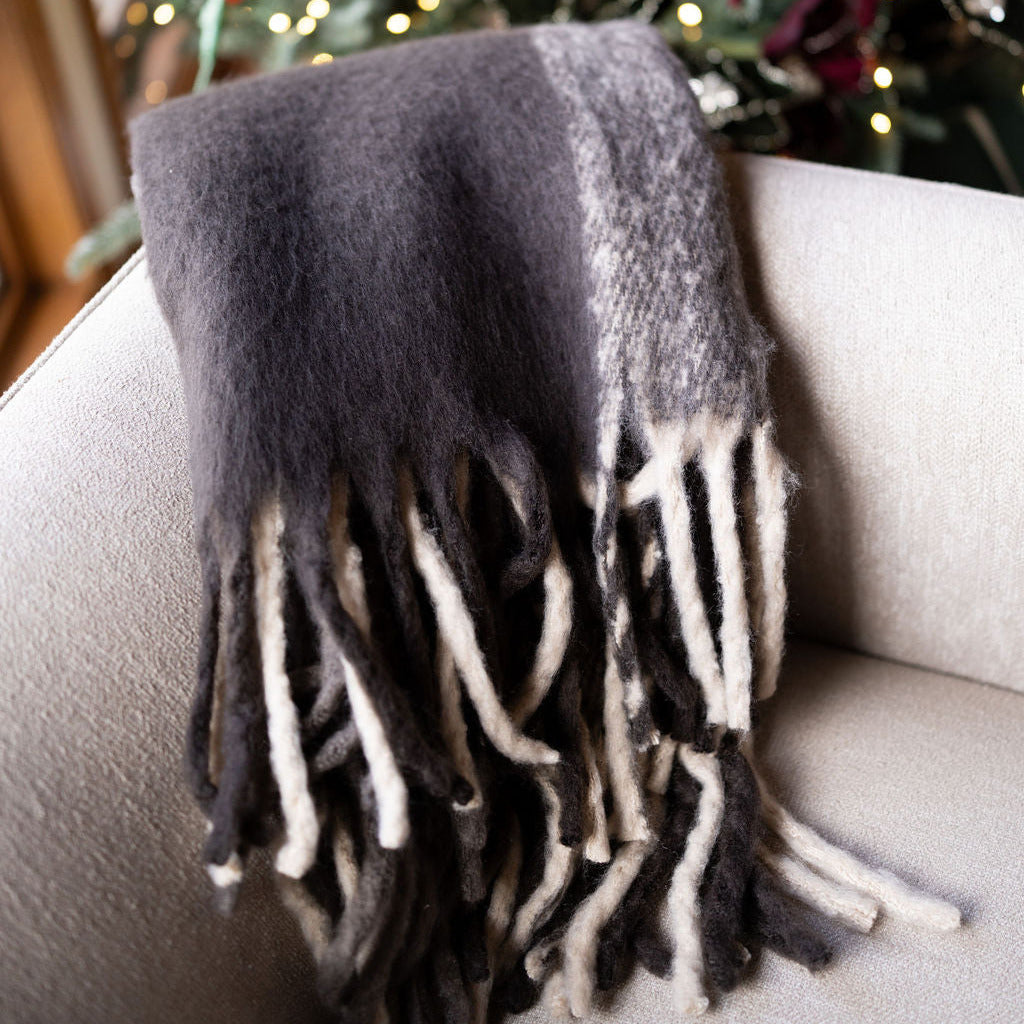 Brown plaid, super soft blanket with tassels on a beige chair