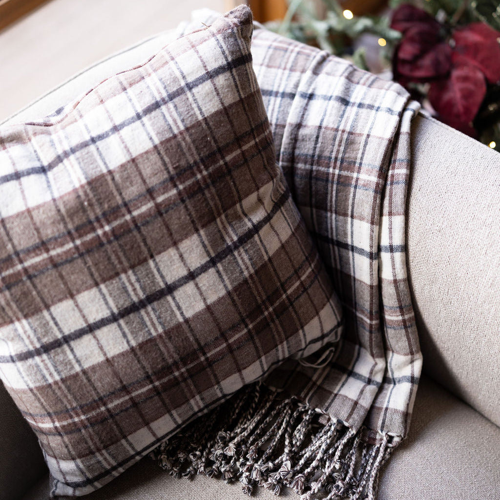 Brown and black cozy reversible pillow with matching blanket on beige chair